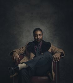 a man sitting in a chair wearing a coat and tie