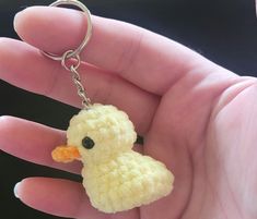 a hand holding a tiny yellow duck keychain