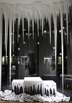 icicles are hanging from the ceiling in front of a store window with tables and benches