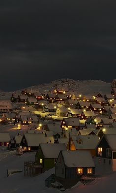 the town is covered in snow and lit up at night with lights shining on it