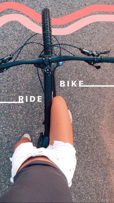 the legs of a person riding a bike on pavement with pink and white lines behind them