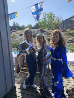 three girls dressed in costumes standing on a deck