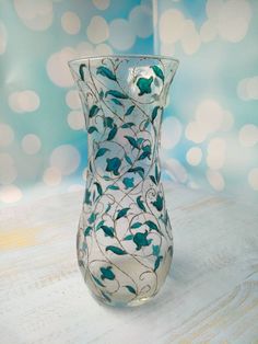 a glass vase sitting on top of a wooden table next to a blue and white wall