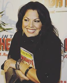 a woman is smiling while holding a book