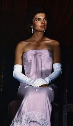 a woman in a purple dress and white gloves