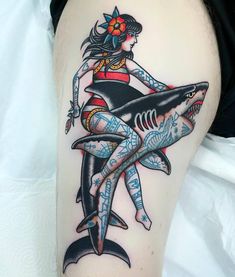 a woman is sitting on top of a shark with an arrow in her hair and tattoos