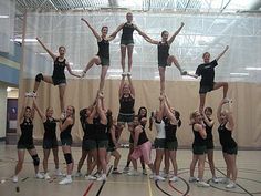 a group of young women standing on top of each other in front of a basketball court