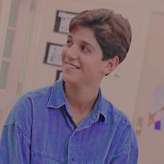 a young boy in a blue shirt is smiling