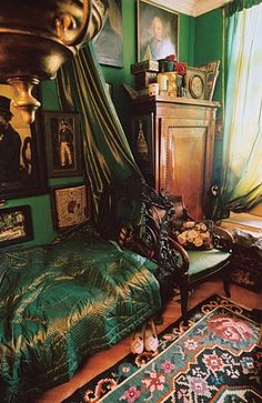 a bedroom with green walls and pictures on the wall next to a bed covered in a canopy