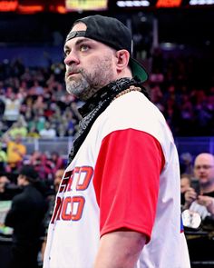 a man in a red and white shirt is looking off to the side while people watch