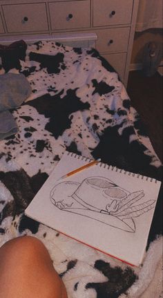 a person's feet on a bed with a cow print comforter and notebook