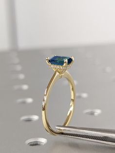 a gold ring with an oval shaped blue stone surrounded by small white diamonds on a metal surface