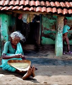 an old woman sitting on the ground next to a basket