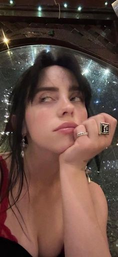 a woman with her hand on her chin looking up at the camera while wearing a ring