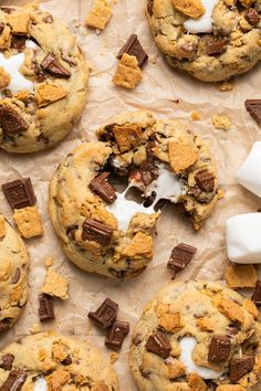 chocolate chip cookies with marshmallows and graham crackers are on parchment paper