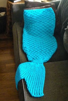 a blue knitted mermaid tail sitting on top of a couch