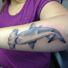 a woman wearing a purple shirt with a shark tattoo on it's arm and wrist