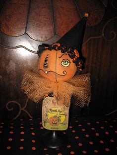 an orange scarecrow doll sitting on top of a black table next to a lamp