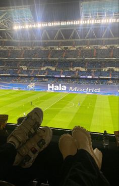 people are sitting in the stands at a soccer stadium with their feet up on the seats