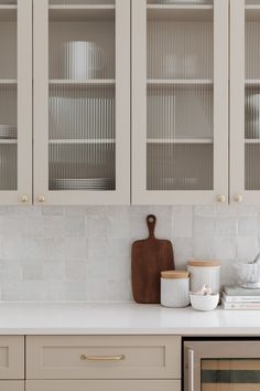 a kitchen with white cabinets and wooden cutting board