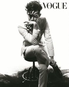 a black and white photo of a man in a suit sitting on top of a stool