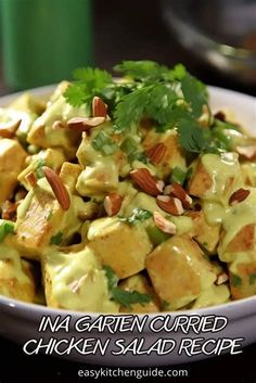 a white bowl filled with chicken salad and topped with cilantro, almonds