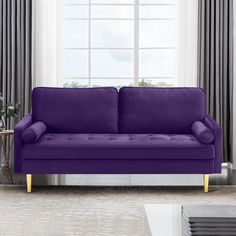 a purple couch sitting in front of a window