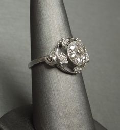 Antique Circa 1930 Constructed of 10KT White Gold with a Central 14KT White Gold Cluster of 7 Genuine Earth-Mined Old Round European cut Diamonds weighing a total of approximately 0.50 carats H-J Color; VS1-I1 Clarity (although most in the VS2-SI1 range) Cluster measuring approximately 8.2mm in diameter with 5 Genuine Earth-Mined Nearly Colorless Nearly Flawless to Slightly Included Round Single cut Smaller Accent Diamonds weighing a total of approximately 0.08 carats F-G Color; VVS1-SI1 Clarity Collectible Cluster Ring With Brilliant Cut, Vintage Diamond White Diamond Ring With Halo Setting, Vintage Diamond White Ring With Halo Setting, Classic Collectible Cluster Ring With Diamond Cut, Victorian Style Diamond White Cluster Ring, Classic Hallmarked Cluster Ring In 14k White Gold, Vintage Cluster Ring With Halo Setting In Diamond White, Vintage Diamond White Diamond Ring For Formal Occasions, Classic Hallmarked 14k White Gold Cluster Ring