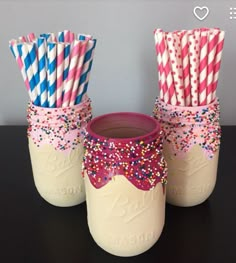 two mason jars with pink and blue striped straws in them, one is filled with sprinkles