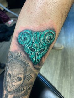 a man's arm with a green heart tattoo on it