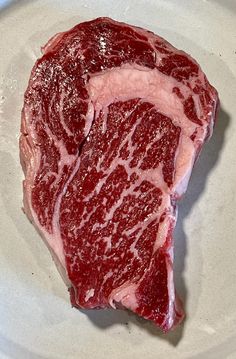 a piece of raw meat sitting on top of a white plate