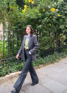 a woman walking down the sidewalk in front of trees