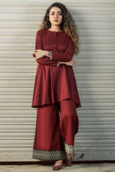 Exhibiting elegant embroidery and stitch detailing, this maroon silk trouser suit which is sure to set you apart from the rest.This round neck and full sleeve suit is plain.Teamed up with silk palazzo pant in maroon color with maroon net dupatta.Palazzo pant has lace work.Dupatta is plain.This trouser suit can be customised up to maximum size available in inches 68. Slight color variation may occur due to photographic reasons. Kurta Pants, Frock Fashion, Dress Book, Trouser Suit, Stylish Short Dresses, Pakistani Dresses Casual, Pakistani Fashion Party Wear, Casual Wear Dress, Simple Pakistani Dresses