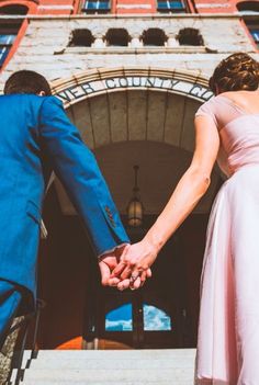 a bride and groom hold hands as they walk down the steps