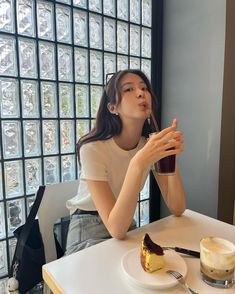 a woman sitting at a table with a piece of cake and coffee in front of her