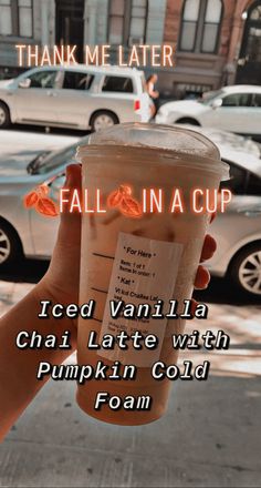 a person holding up a cup of iced vanilla chai latte with pumpkin cold foam