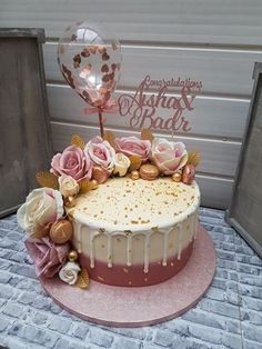 a cake decorated with flowers and balloons on top of a pink platter next to a door