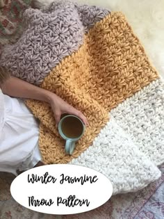 a woman laying on top of a rug holding a cup of coffee