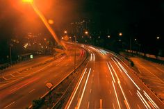 an empty highway at night with light streaks on the road and street lamps in the distance