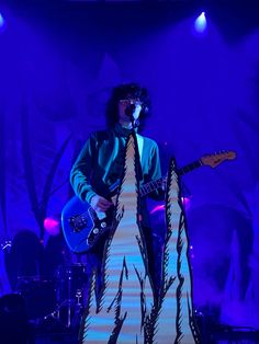 a man standing on top of a stage holding a guitar