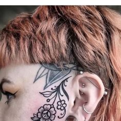 a woman with tattoos on her face and behind the ear