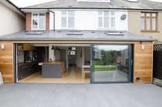 an open garage door in front of a large house with wood siding and glass doors