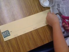 a person cutting up a piece of paper on top of a wooden table