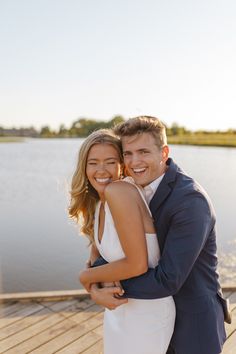 a man and woman hugging each other on a dock