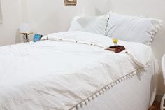 a bed with white linens and pillows in a small room next to a lamp