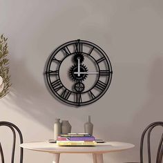 a clock that is on the wall above a dining room table with chairs and vases