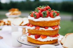 a cake with strawberries on top is sitting on a table next to other desserts