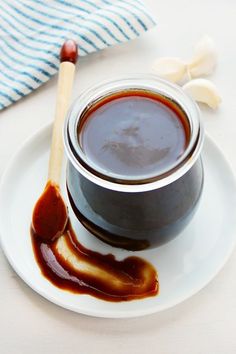 a jar of sauce sitting on top of a white plate next to a wooden spoon