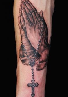 a black and white photo of a praying hand with a rosary on it's arm