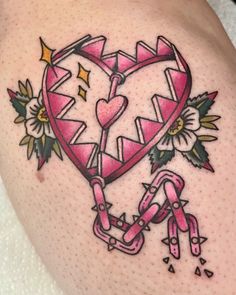 a pink heart tattoo on the back of a woman's thigh, with flowers and chains around it